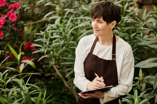 Kendine güvenen, güzel bir kadın hayat dolu bitkilerle dolu bir serada özenle çalışıyor..