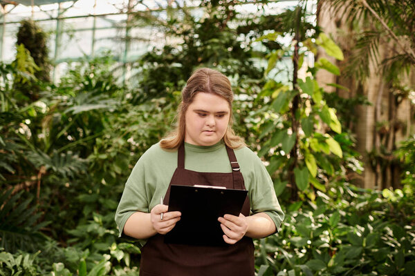 Young woman with Down syndrome shows confidence while working in a lively greenhouse.