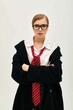 Genç bir kadın, minimalist bir stüdyo arkaplanına karşı duran şık bir kıyafete güveniyor..