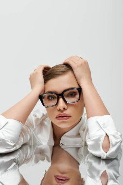 Zarif bir kıyafeti olan genç bir kadın modern bir stüdyoda düşünceli bir şekilde poz veriyor..