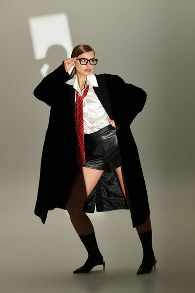 Sophisticated young woman poses confidently in an elegant studio setting, flaunting a chic outfit.