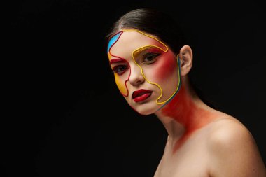 Genç bir kadın canlı bir yüz sanatı sergiliyor, yaratıcılığını siyah bir zemine karşı sergiliyor..