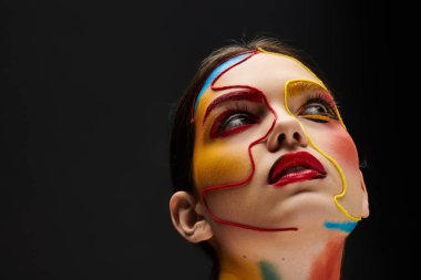 Genç bir kadın canlı yüz sanatı sergiliyor, cesur renkler ve şık bir makyaj sergiliyor..