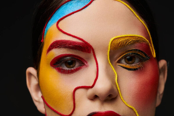 Молодая женщина показывает художественные краски лица в ярких цветах и сложных конструкций, источая красоту.
