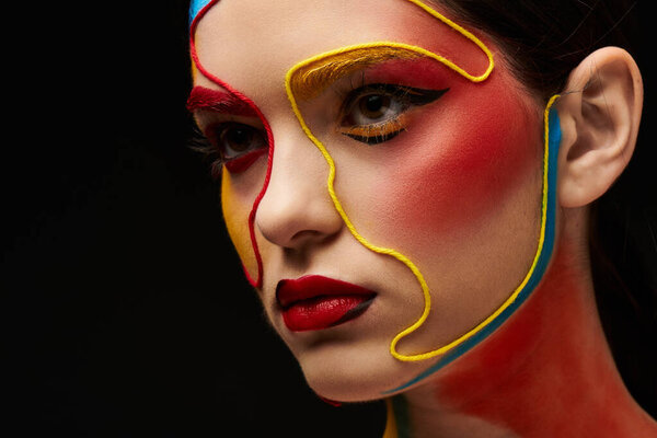 Молодая женщина демонстрирует потрясающее лицо с яркими красками и сложными узорами.