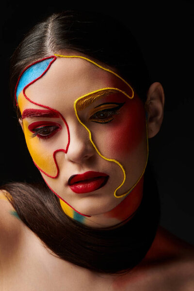 Молодая женщина демонстрирует яркую краску для лица и яркий макияж в студии.