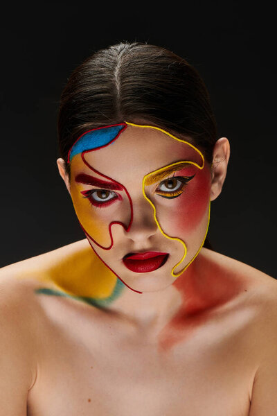 Молодая женщина демонстрирует яркое искусство лица, подчеркивая свою креативность и уверенность.