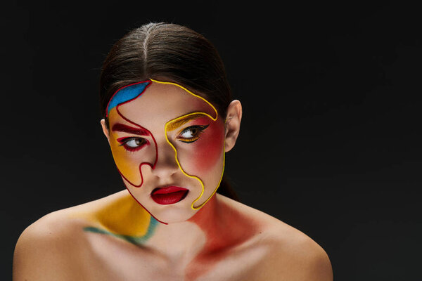 Молодая красивая женщина демонстрирует красочное лицо с замысловатыми деталями на темном фоне.