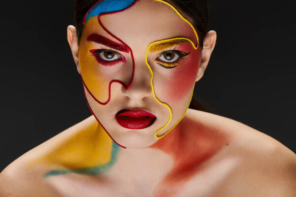 Молодая женщина демонстрирует яркое лицо искусства, смешивая цвета, которые повышают ее красоту и стиль.