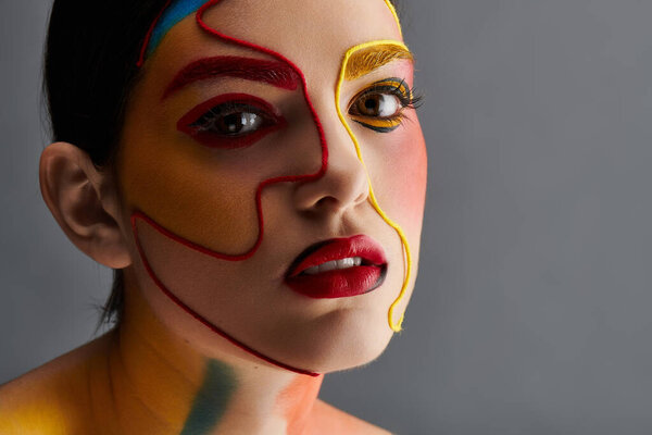 Живое искусство лица украшает молодую красивую женщину, элегантно позирующую в творческой обстановке.