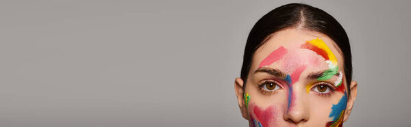Молодая женщина демонстрирует красочное лицо, которое подчеркивает ее творчество и стиль.