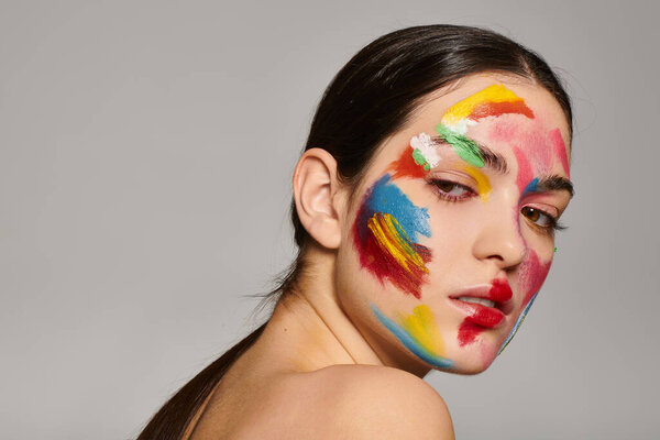Молодая, красивая женщина демонстрирует яркое искусство лица, излучающее художественное очарование.