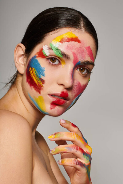 Молодая женщина элегантно демонстрирует яркое лицо с красочной краской на ее чертах.