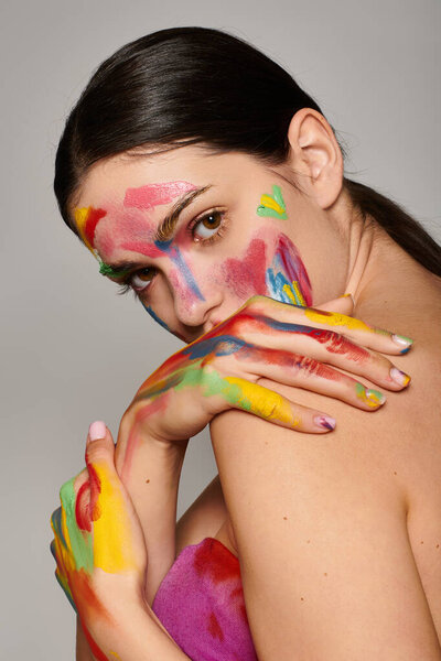 Молодая женщина демонстрирует яркую краску для лица, подчеркивая ее творчество и стиль.