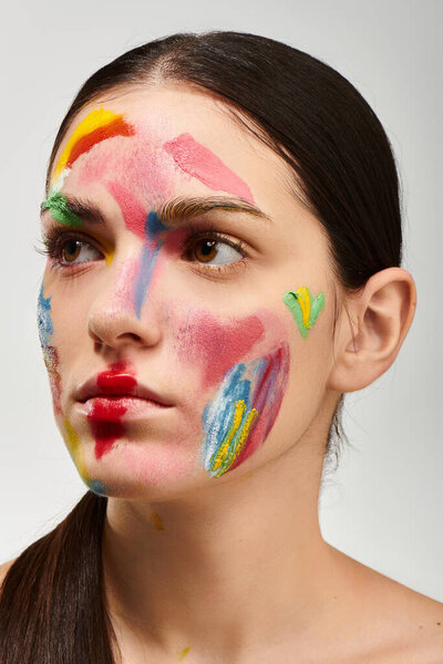 Молодая женщина демонстрирует яркое лицо с красочной краской и завораживающим макияжем.