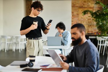 İki birey, doğal ışıkla dolu canlı bir ofis alanında çeşitli görevlerde bulunurlar..