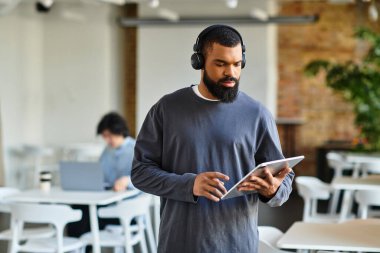 Bir adam bir tablette geziniyor, müzik içinde kayboluyor, bir meslektaşı yakınlardaki canlı bir ofiste çalışıyor..