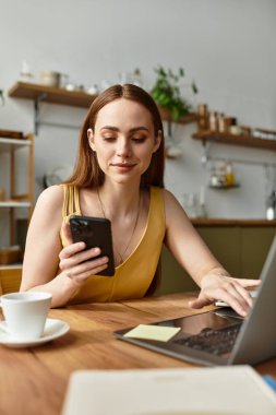 Zeki ve hayat dolu genç bir kadın bir kafede görevlerini dengelemek için akıllı telefonuyla meşgul oluyor..