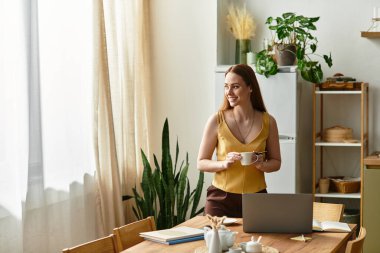 Genç bir kadın güneşli bir mutfakta yeşil bitkiler ve hoş bir dekorla kahveyi seviyor..