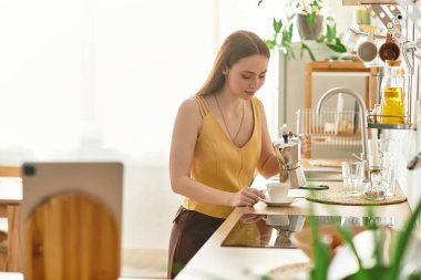 Genç bir kadın güneşli bir mutfakta kahve yapıyor, bitkilerle çevrili, taze bir hava yakalıyor..