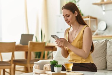 Genç ve güzel bir kadın rahat bir şekilde otururken akıllı telefondan kayarak zaman geçirmekten hoşlanıyor..