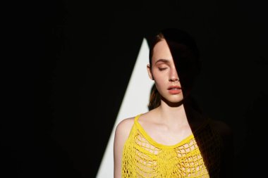 Genç bir kadın, eşsiz bir ışık ve gölge oyununda zarafetle duruyor. Huzur saçıyor..