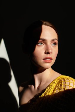 Genç bir kadın çarpıcı bir ışık ve gölge oyununda etkileyici özelliklerini vurgular..