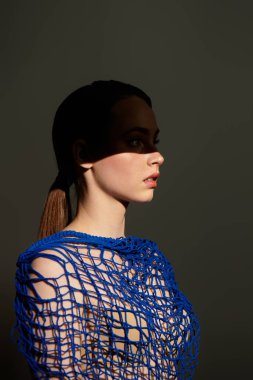 Eşsiz mavi elbiseli zarif genç bir kadın zarif yüz hatlarını ve gölgelerini ön plana çıkarıyor..