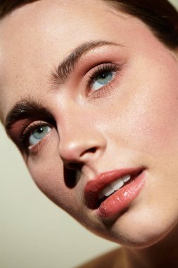 Genç ve güzel bir kadın düşünceli bir şekilde, çarpıcı mavi gözlerini ve pürüzsüz cildini ön plana çıkarıyor..