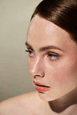 Genç bir kadın kusursuz cildiyle zarafet saçar ve yumuşak bir arka planda çarpıcı gözleriyle.