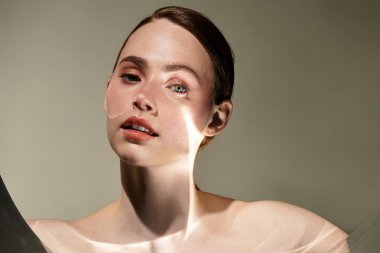 Genç, güzel bir kadın zarif bir şekilde bakıyor. Yumuşak bir ışık yüzlerinde dans ederken..