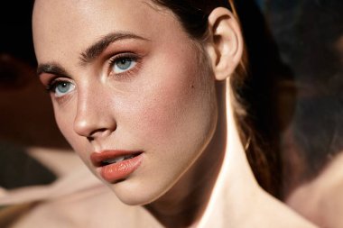 Genç bir kadın büyüleyici mavi gözlerini ve taze parıltısını gösterir, sıcacık ışıkta güzel bir şekilde yakalanır..