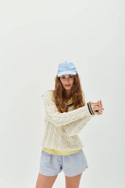 Rahat süveter ve şapkalı genç bir kadın neşe saçarak poz veriyor..