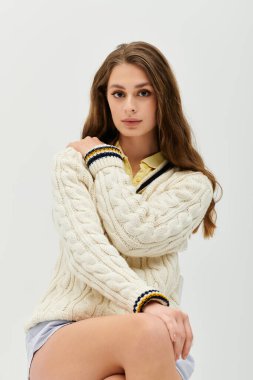 Genç bir kadın, sarı bir dokunuşla örülmüş bir kazakla güzellik ve güven saçar..