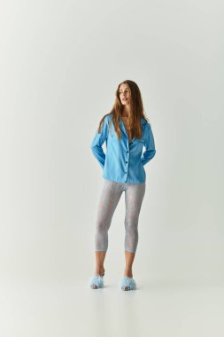 Genç ve güzel bir kadın, minimalist kapalı bir ortamda kendinden emin bir şekilde duruyor..