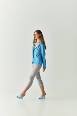 Genç bir kadın kendine güvenerek yürüyor, şık kıyafetini parlak bir mekanda sergiliyor..