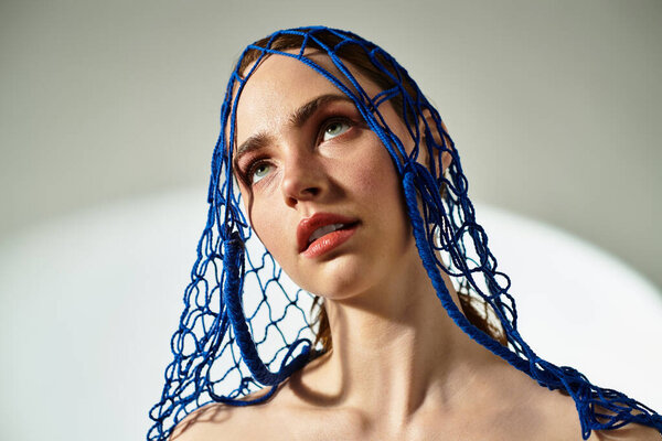 A stunning young woman captivates with her gaze, a blue net headpiece highlighting her beauty.