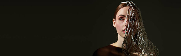 Молодая женщина выставляет напоказ художественную прическу при мягком освещении, создавая завораживающую атмосферу.