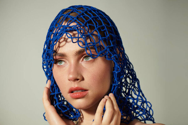 Молодая красивая женщина демонстрирует свои очаровательные черты, нежно держа лицо.