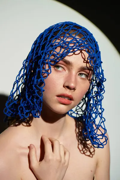 Çarpıcı mavi başlıklı kadın zarif poz veriyor, güzelliğini ve eşsiz tarzını vurguluyor..