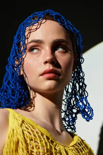 Genç bir kadın eşsiz mavi saçlarını ve büyüleyici ifadesini parlak doğal ışıkta sergiliyor..