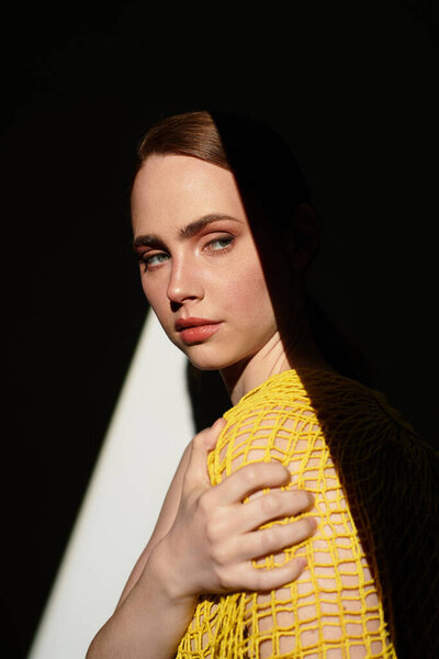 Молодая женщина элегантно позирует в ярком наряде, демонстрируя свои черты и яркие тени..