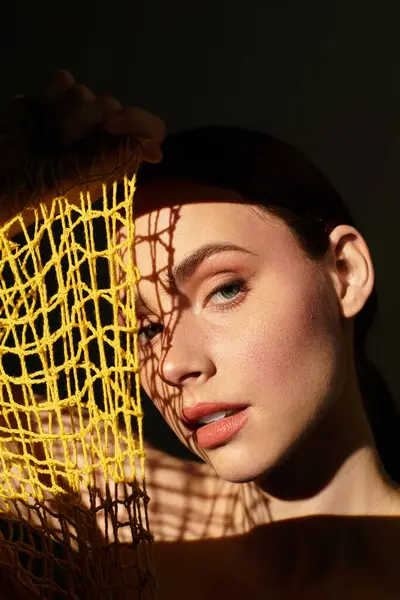 Sevimli genç bir kadın parlak ağ kumaşıyla ışığı ve gölgeyi keşfeder..