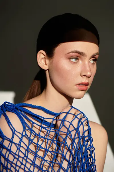 Doğal makyajlı ve şık mavi ağlı genç bir kadın özgüven ve cazibe sergiliyor.