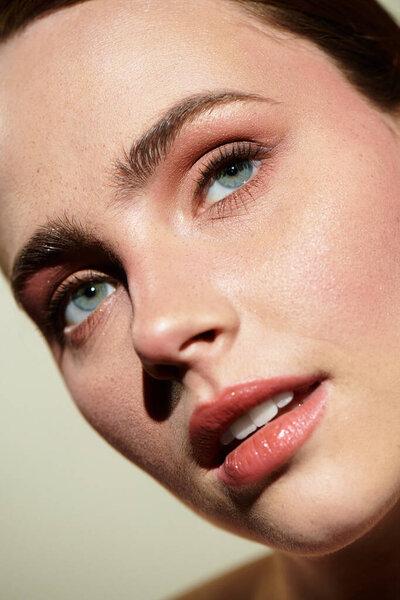 A young beautiful woman gazes thoughtfully, highlighting her striking blue eyes and flawless skin.