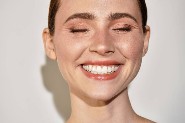 Молодая красивая женщина сияет счастьем, показывая свою светящуюся кожу и сияющую улыбку.