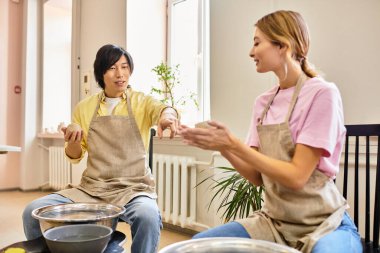 Genç bir çift neşeli bir şekilde canlı bir sanat stüdyosunda çömlek yapıyorlar..