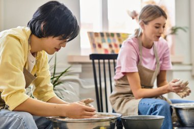 Genç bir çift, yaratıcı bir çömlek seansında killeri neşeyle şekillendirir..