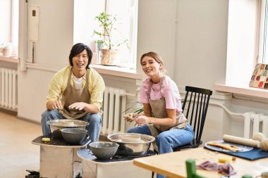 Genç bir çift eğlenceli ve eğlenceli bir çömlekçilik seansından zevk alır, birlikte güler ve yaratırlar..