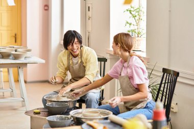 Genç bir çift, parlak bir stüdyoda çömlek yaparken kahkaha ve yaratıcılığını paylaşıyor..